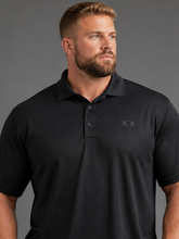 Load image into Gallery viewer, A man wearing a black short-sleeve polo shirt with a small tonal embroidered logo on the left chest, photographed against a solid gray studio background.