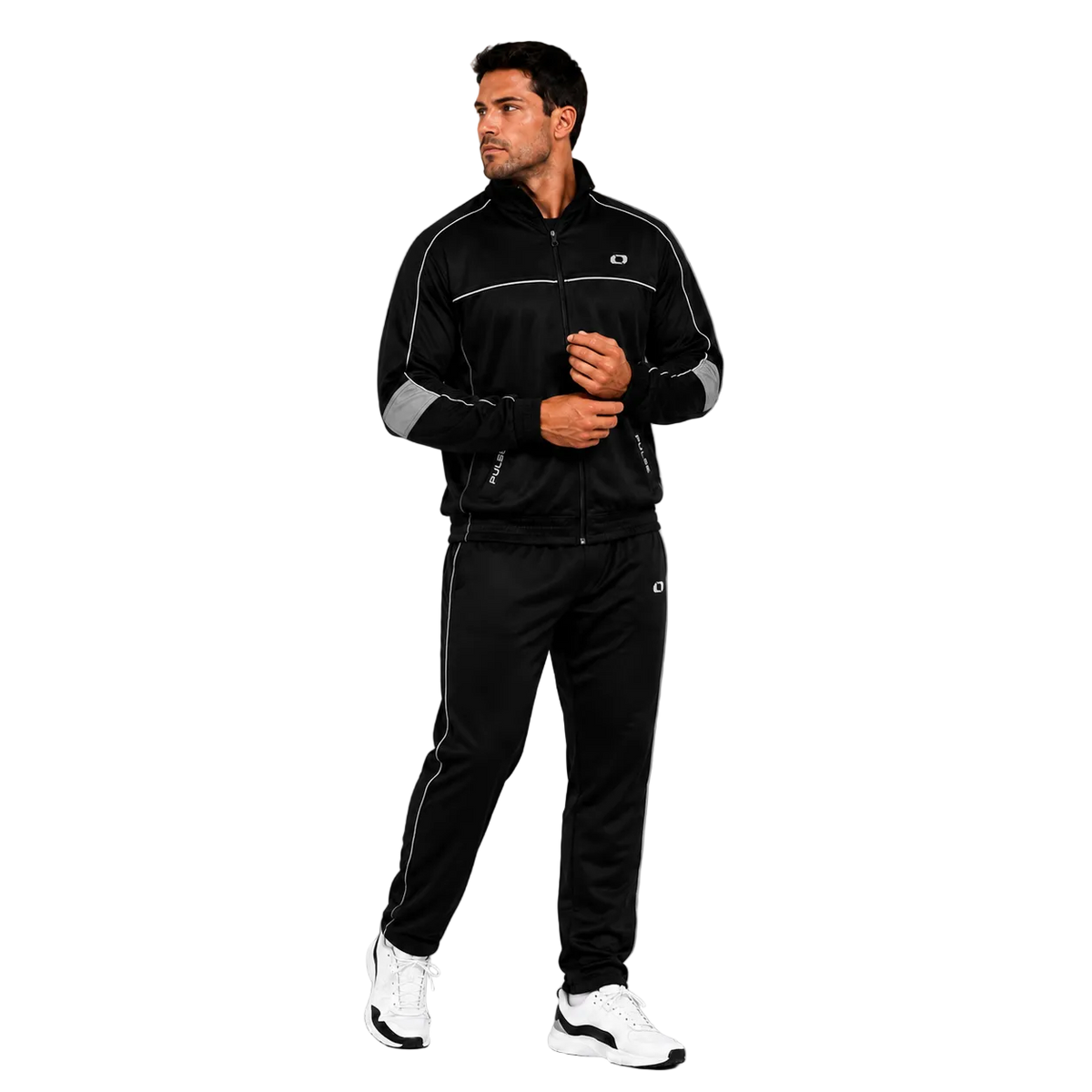 A man modeling a black athletic tracksuit with white piping and zippers, featuring a zip-up jacket and matching jogger pants, paired with white sneakers, against a gray studio background.