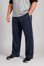 Load image into Gallery viewer, A person wearing navy blue athletic pants with a gray and black shirt, standing against a light gray studio background.
