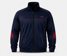Load image into Gallery viewer, A navy blue track jacket with red piping, red sleeve panels, and a red logo on the left chest, displayed against a light gray background.

