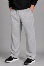 Load image into Gallery viewer, A person wearing heather gray sweatpants with a black hoodie and black sneakers, shown from the waist down against a plain gray studio background.
