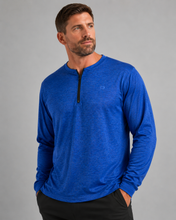 Load image into Gallery viewer, A man wearing a royal blue long-sleeve quarter-zip athletic shirt with a small embroidered logo on the left chest, paired with black pants, against a solid gray studio background.

