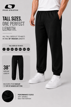 Load image into Gallery viewer, A model wearing black Pulse Athletics tall fleece jogger pants with white sneakers, shown against a light gray background with promotional text highlighting tall sizing and a 38-inch inseam length.
